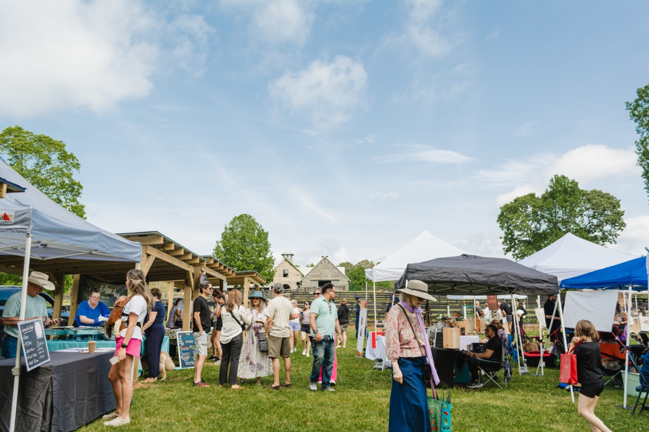 Visitors browse outdoor stalls and vendor tents at the Serenbe Farmers Market.